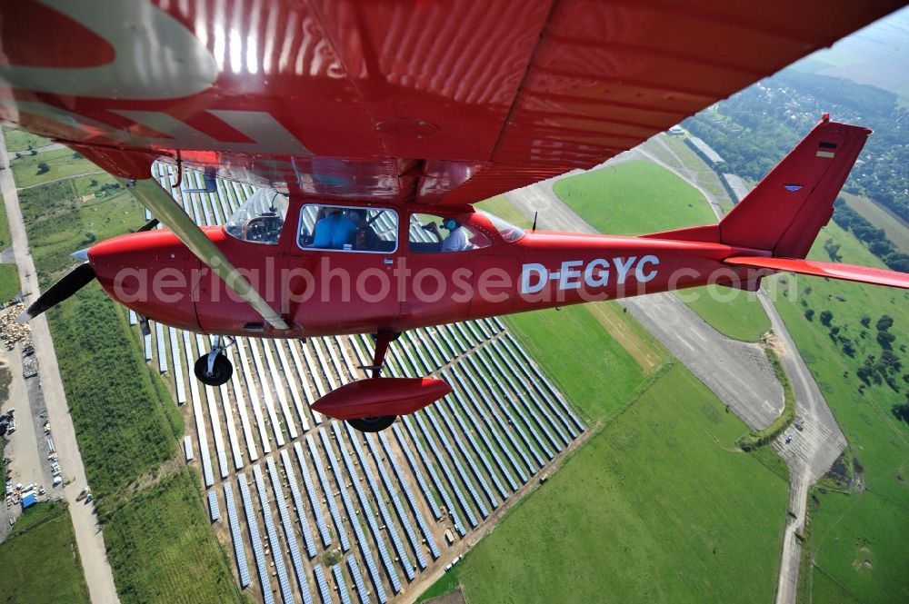 Werneuchen from the bird's eye view: Bright red Cessna 172 D-EGYC of the agency euroluftbild.de in flight over the airfield in Werneuchen in the state Brandenburg, Germany