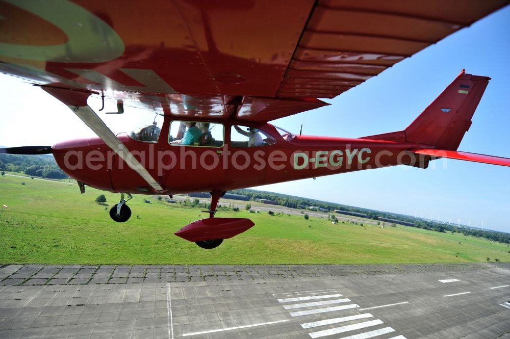 Werneuchen from the bird's eye view: Bright red Cessna 172 D-EGYC of the agency euroluftbild.de in flight over the airfield in Werneuchen in the state Brandenburg, Germany