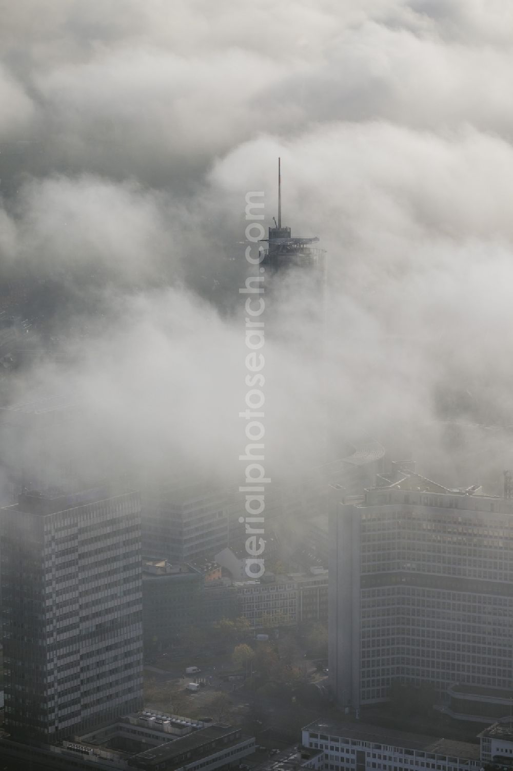 Essen from above - View of the RWE tower shrouded with fog and an impressive cloud bank over the city center of Essen in the state North Rhine-Westphalia. The autumn weather clouds are surrounding the skyscraper headquarters of energy supplier RWE at Opernplatz and form a thick cover over the Ruhr region city