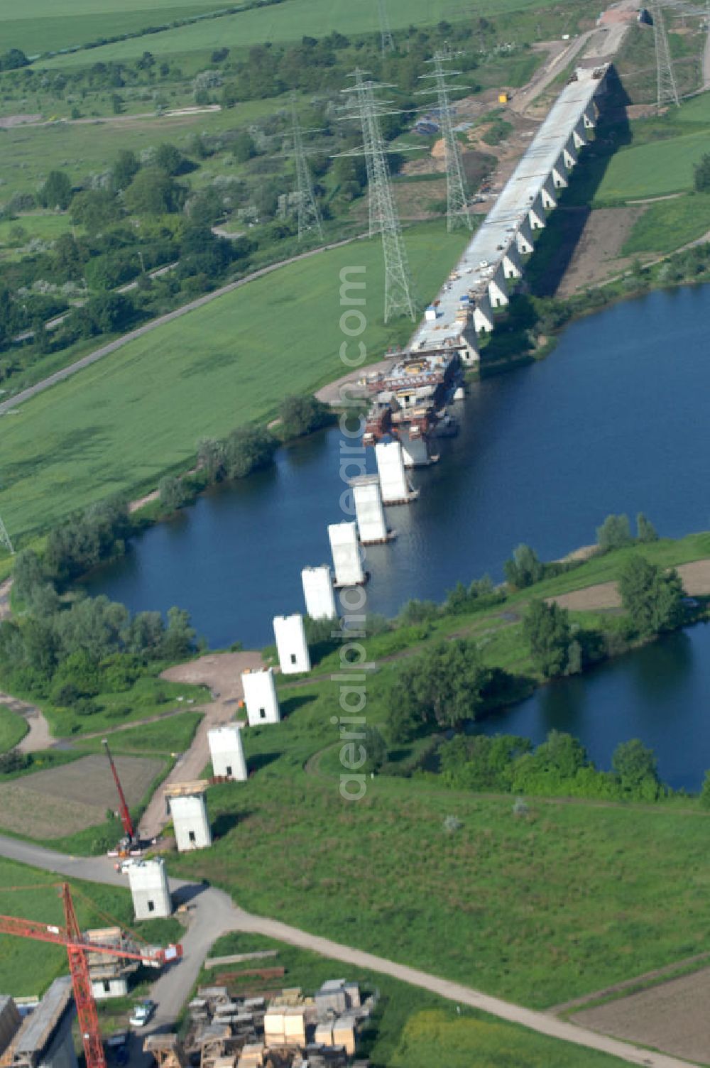 Rattmannsdorf from the bird's eye view: Blick auf die Vorschub- Bauarbeiten an der Saale-Elster-Talbrücke über den Rattmannsdorfer See. Das Beton- Viadukt mit insgesamt 8, 5 Kilometern Länge wird teilweise mit großen Baugerüsten in so genannter Vor-Kopf-Bauweise errichtet, bei der zur Schonung der Umwelt alle Arbeitsschritte von der fertigten Brücke aus erfolgen und keine Baustraßen notwendig sind. Die ICE - Neubaustrecke im Projekt VDE 8 Nürnberg-Berlin der Deutschen Bahn soll 2015 in Betrieb gehen und wird das bisher längste Brückenbauwerk Deutschlands sein. Bauausführende Firmen sind die Hochtief Construction AG, Adam Hörnig, Gerdum und Breuer; Franki Grundbau; Doka Schalungstechniker; BBV Vorspanntechnik; Röro Traggerüstsysteme; Oevermann Hoch- und Tiefbau, Teupe & Söhne Gerüstbau GmbH, Alpine Bau und Arcelormittal. View of the construction of the Saale-Elster Viaduct on the Rattmannsdorfer lake.