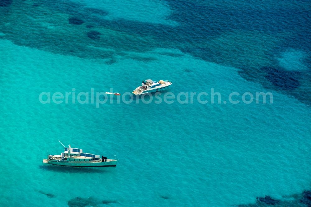 Aerial image Ses Covetes - Ships and water surface at the seaside Cala Magrana in Ses Covetes in Islas Baleares, Spain