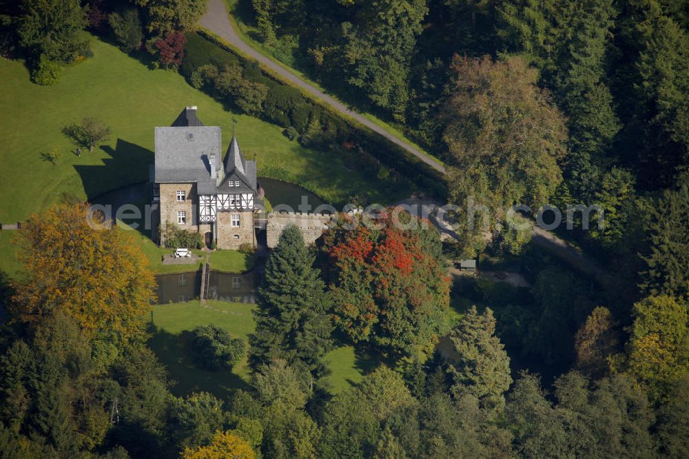 Meinerzhagen from the bird's eye view: Herbstlicher Blick auf das Schloss Badinghagen - es ist ein Wasserschloss, das dicht an der Grenze zum Bergischen Land südlich von Meinerzhagen steht und 1902 stark modernisiert wurde. Seine Gräften werden von der Agger gespeist. Im Werdener Propsteiregister wurde das Schloss im Jahr 1160 als Lehnsgut erstmals genannt. Im Besitz der Badinghagens ist es nachweislich seit dem Jahr 1363. Nach Aussterben der Familie ging es 1509 über Friedrich von Karthausen durch Verkauf im Jahr 1642 an Friedrich von Neuhoff. Drei Generationen später war Conrad Caspar von Nagel, ein Sohn der Erbtochter, Eigentümer des Schlosses Badinghagen. Die heutige, mittlerweile mehrmals umgebaute Anlage hat nur ungefähr den Grundriss des früheren Bauwerks, das etwa Mitte des 17. Jahrhunderts die Eheleute Engelbert von Neuhoff und Anna Margarethe von Scheid errichten ließen.