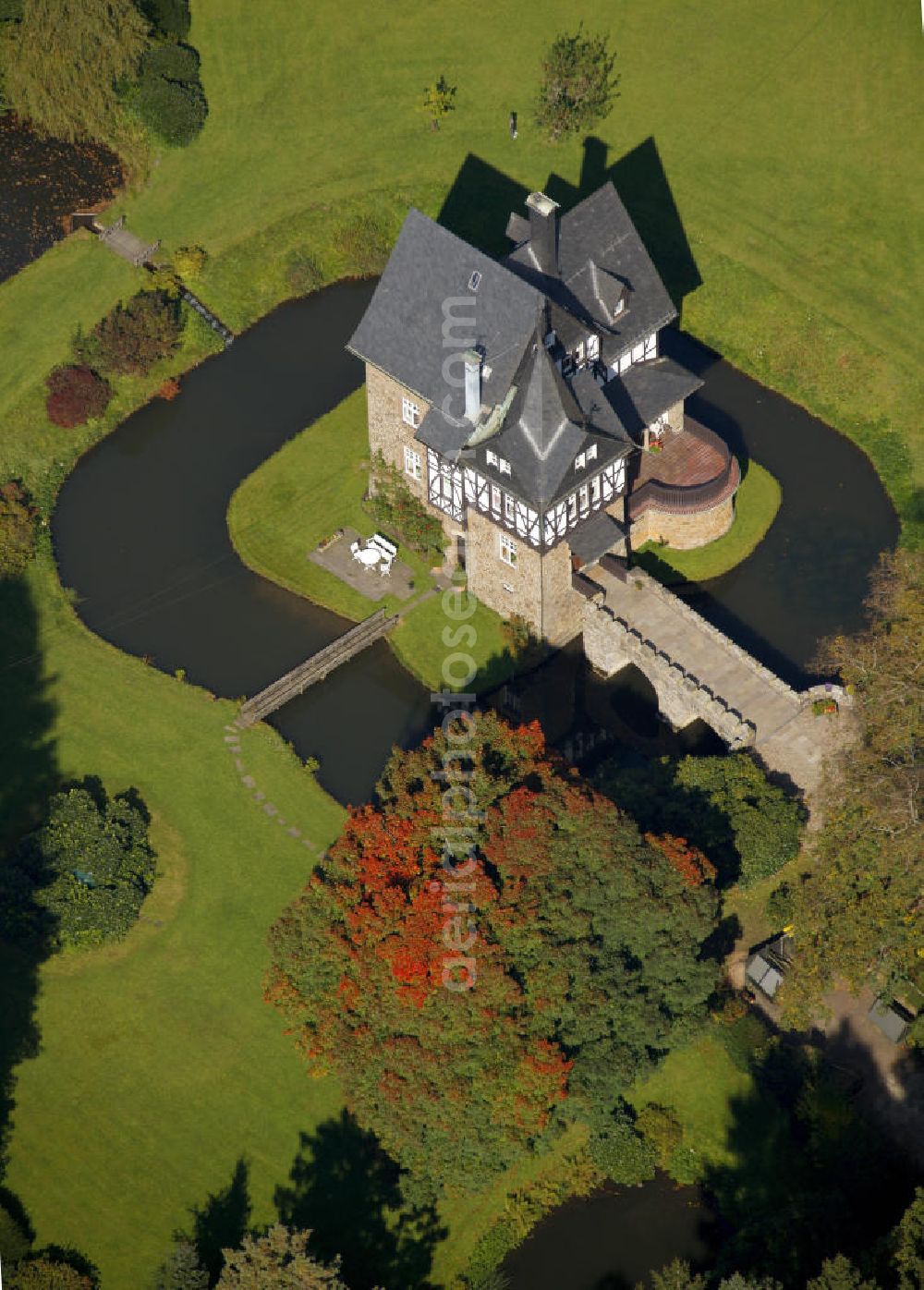 Aerial photograph Meinerzhagen - Herbstlicher Blick auf das Schloss Badinghagen - es ist ein Wasserschloss, das dicht an der Grenze zum Bergischen Land südlich von Meinerzhagen steht und 1902 stark modernisiert wurde. Seine Gräften werden von der Agger gespeist. Im Werdener Propsteiregister wurde das Schloss im Jahr 1160 als Lehnsgut erstmals genannt. Im Besitz der Badinghagens ist es nachweislich seit dem Jahr 1363. Nach Aussterben der Familie ging es 1509 über Friedrich von Karthausen durch Verkauf im Jahr 1642 an Friedrich von Neuhoff. Drei Generationen später war Conrad Caspar von Nagel, ein Sohn der Erbtochter, Eigentümer des Schlosses Badinghagen. Die heutige, mittlerweile mehrmals umgebaute Anlage hat nur ungefähr den Grundriss des früheren Bauwerks, das etwa Mitte des 17. Jahrhunderts die Eheleute Engelbert von Neuhoff und Anna Margarethe von Scheid errichten ließen.