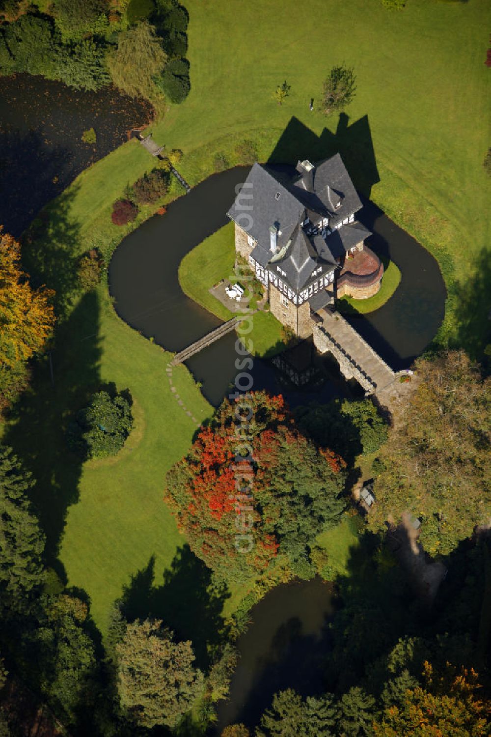 Meinerzhagen from the bird's eye view: Herbstlicher Blick auf das Schloss Badinghagen - es ist ein Wasserschloss, das dicht an der Grenze zum Bergischen Land südlich von Meinerzhagen steht und 1902 stark modernisiert wurde. Seine Gräften werden von der Agger gespeist. Im Werdener Propsteiregister wurde das Schloss im Jahr 1160 als Lehnsgut erstmals genannt. Im Besitz der Badinghagens ist es nachweislich seit dem Jahr 1363. Nach Aussterben der Familie ging es 1509 über Friedrich von Karthausen durch Verkauf im Jahr 1642 an Friedrich von Neuhoff. Drei Generationen später war Conrad Caspar von Nagel, ein Sohn der Erbtochter, Eigentümer des Schlosses Badinghagen. Die heutige, mittlerweile mehrmals umgebaute Anlage hat nur ungefähr den Grundriss des früheren Bauwerks, das etwa Mitte des 17. Jahrhunderts die Eheleute Engelbert von Neuhoff und Anna Margarethe von Scheid errichten ließen.