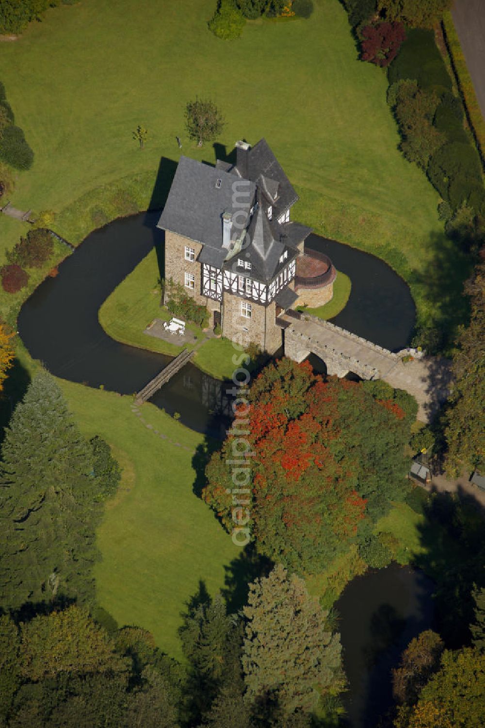 Meinerzhagen from the bird's eye view: Herbstlicher Blick auf das Schloss Badinghagen - es ist ein Wasserschloss, das dicht an der Grenze zum Bergischen Land südlich von Meinerzhagen steht und 1902 stark modernisiert wurde. Seine Gräften werden von der Agger gespeist. Im Werdener Propsteiregister wurde das Schloss im Jahr 1160 als Lehnsgut erstmals genannt. Im Besitz der Badinghagens ist es nachweislich seit dem Jahr 1363. Nach Aussterben der Familie ging es 1509 über Friedrich von Karthausen durch Verkauf im Jahr 1642 an Friedrich von Neuhoff. Drei Generationen später war Conrad Caspar von Nagel, ein Sohn der Erbtochter, Eigentümer des Schlosses Badinghagen. Die heutige, mittlerweile mehrmals umgebaute Anlage hat nur ungefähr den Grundriss des früheren Bauwerks, das etwa Mitte des 17. Jahrhunderts die Eheleute Engelbert von Neuhoff und Anna Margarethe von Scheid errichten ließen.