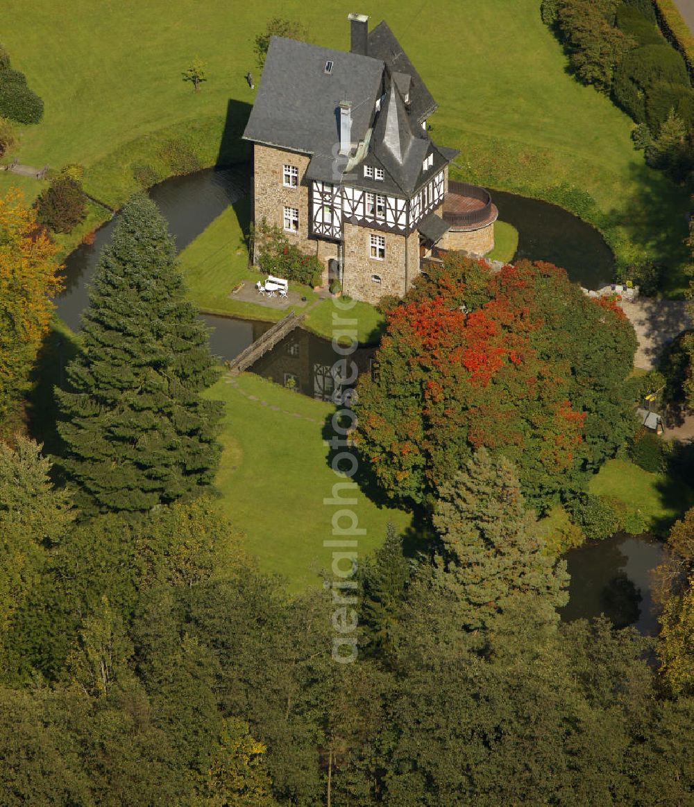 Aerial photograph Meinerzhagen - Herbstlicher Blick auf das Schloss Badinghagen - es ist ein Wasserschloss, das dicht an der Grenze zum Bergischen Land südlich von Meinerzhagen steht und 1902 stark modernisiert wurde. Seine Gräften werden von der Agger gespeist. Im Werdener Propsteiregister wurde das Schloss im Jahr 1160 als Lehnsgut erstmals genannt. Im Besitz der Badinghagens ist es nachweislich seit dem Jahr 1363. Nach Aussterben der Familie ging es 1509 über Friedrich von Karthausen durch Verkauf im Jahr 1642 an Friedrich von Neuhoff. Drei Generationen später war Conrad Caspar von Nagel, ein Sohn der Erbtochter, Eigentümer des Schlosses Badinghagen. Die heutige, mittlerweile mehrmals umgebaute Anlage hat nur ungefähr den Grundriss des früheren Bauwerks, das etwa Mitte des 17. Jahrhunderts die Eheleute Engelbert von Neuhoff und Anna Margarethe von Scheid errichten ließen.