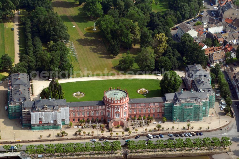 Wiesbaden from above - Im Blick das Schloss Biebrich während der Restaurierung. Fürst Georg August Samuel von Nassau-Idstein ließ sein 1701 begonnenes Gartenhaus durch Julius Ludwig Rothweil bis 1703 zu einem Wohnschlösschen ausbauen, in den Folgejahren weiter östlich ein identisches Gegenstück errichten und ab 1708 beide Bauteile durch einen Mittelbau mit Rotunde verbinden. Seit 1929 findet jährlich an Pfingsten das Internationale Reitturnier im Schlosspark statt. Das Schloss, das im Besitz des Landes Hessen ist, wird vom Hessischen Immobilienmanagement verwaltet. Es dient als repräsentatives Gebäude für Empfänge der Landesregierung und als Standesamt. Außerdem sind mehrere Behörden im Schloss untergebracht, darunter das Hessische Landesamt für Denkmalpflege. Seit dem Wiederaufbau des Ostflügels 1982 befindet sich dort die staatliche Filmbewertungsstelle Wiesbaden, eine Einrichtung der Bundesländer, dessen Vorführsaal als Veranstaltungsort für Filme im Schloss genutzt wird.