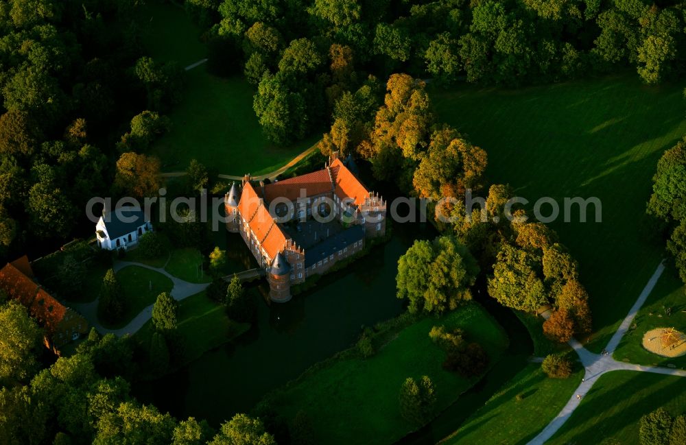 Aerial image Herten - Herten Castle during sunset in Herten in the state of North Rhine-Westphalia. The water castle is located in an old english park and was built in 1376. The late-gothic compound consists of the main building built from brick and including round corner towers and the outer bailey which is located on its own small island. The castle chapel stands between the two