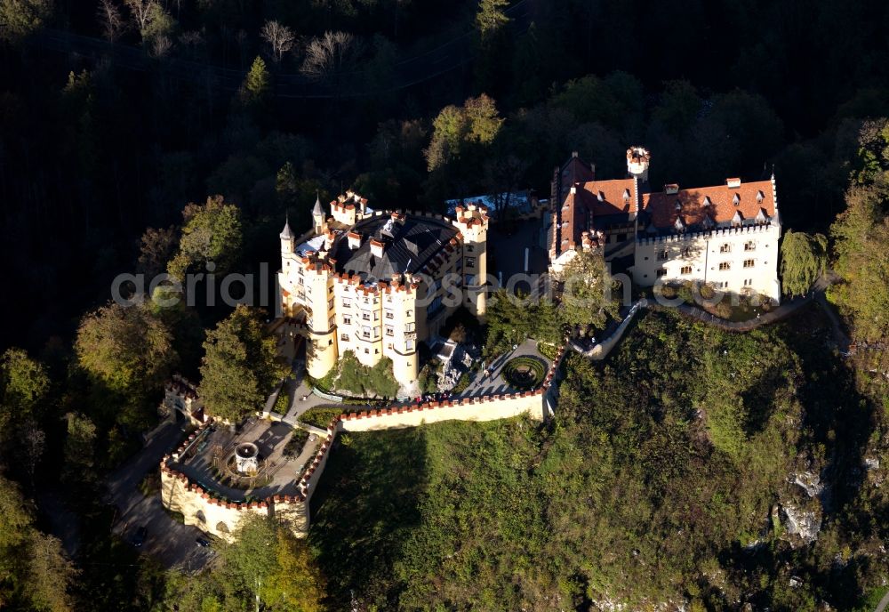 Aerial image Schwangau - Castle Hohenschwangau in Schwangau in the state of Bavaria. The castle is located on a mountain in the borough part of the same name opposite Castle Neuschwanstein. The four storey main building with its yellow facade also has three round towers and a gate building. The compound is surrounded by forest on a rock