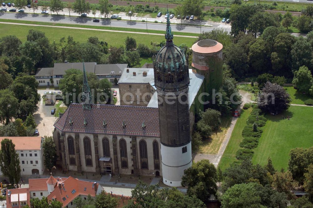 Aerial photograph Lutherstadt Wittenberg - Blick auf das Schloss Wittenberg. Ausgrabungsfunde aus verschiedenen prähistorischen Epochen auf dem Territorium der Lutherstadt lassen bereits eine frühzeitliche Besiedlung des Stadtgebietes vor zirka 10.000 Jahren erkennen. In verschiedenen Epochen entstandene Gebäude zählen zu den bedeutendsten Stätten der deutschen Geschichte. Das Schloss mit seinem 88m hohen neugotischen Kirchturm am westlichen Ende der Stadt zählt zum wichtigsten UNESCO-Weltkulturerbe. Die erste Erwähnung der Burg stammt von 1187. Im Jahre 1340 bauen die Askanier hier ihr eigenes Schloss. Die Urform der Schlosskirche muss 1496 in solch unzureichendem Zustand gewesen sein, dass nach deren Abriss ein Kirchneubau entstand, der erst 1506 beendet wurde. Berühmtheit erlangte sie, als am 31. Oktober 1517 der bis dahin nahezu unbekannte Wittenberger Augustinermönch und Theologieprofessor Martin Luther seine 95 lateinischen Disputationsthesen verbreitete. Heute befinden sich im Schloss eine Jugendherberge, das Riemer-Museum und die stadtgeschichtlichen Sammlungen. Kontakt: Schloss- und Universitätskirche Allerheiligen, Schlossplatz, 06886 Lutherstadt Wittenberg, Tel.: 03491 - 40258