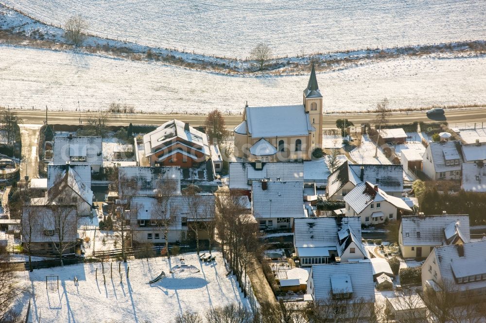 Aerial photograph Arnsberg - Wintry snowy church building of Dietrich Bonhoeffer church in Oeventrop in the state of North Rhine-Westphalia. The protestant church is located on federal highway B7 in the East of the village