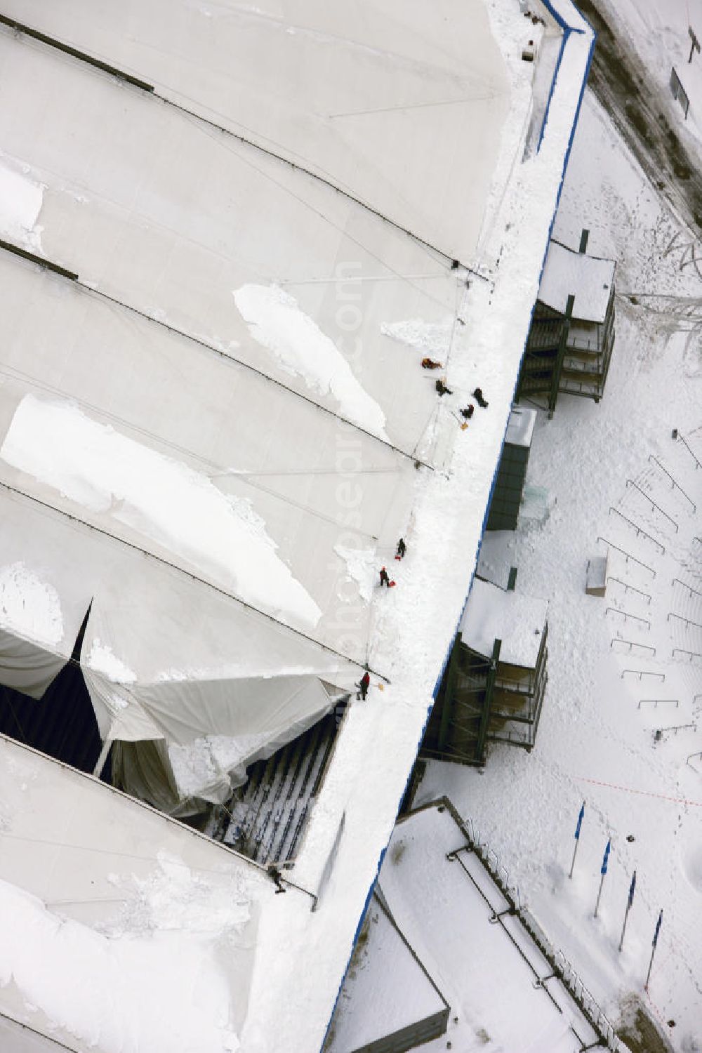 Aerial photograph GELSENKIRCHEN - Einsatzkräfte schieben Schnee vom Dach der Veltins-Arena in Gelsenkirchen. Der Schaden am Dach der Arena des Fußball-Bundesligisten FC Schalke 04 wird immer größer. Durch die Schneemassen auf der multifunktionalen Spielstätte in Gelsenkirchen sind die empfindlichen Dachmembranen inzwischen an sechs Stellen und auf einer Fläche von etwa 6000 Quadratmetern beschädigt. Am Sonntag hatte der Club bereits den für den 30. Dezember vorgesehenen Biathlon-Wettbewerb abgesagt, da die Sicherheit der Zuschauer nicht gewährleistet werden konnte. Snow damage to the roof of the Schalke - Arena in Gelsenkirchen.