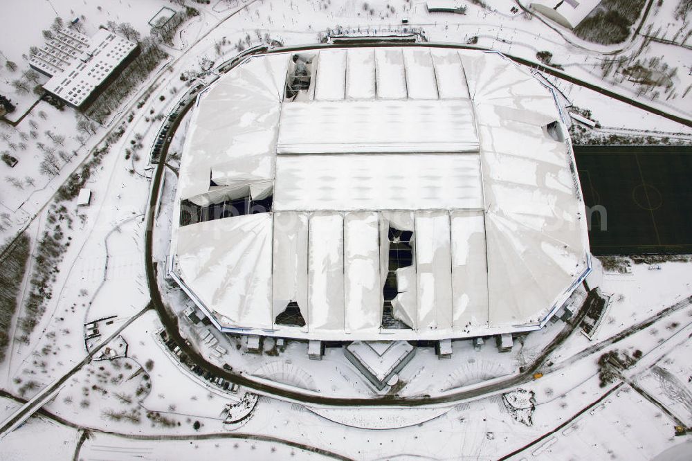 GELSENKIRCHEN from the bird's eye view: Einsatzkräfte schieben Schnee vom Dach der Veltins-Arena in Gelsenkirchen. Der Schaden am Dach der Arena des Fußball-Bundesligisten FC Schalke 04 wird immer größer. Durch die Schneemassen auf der multifunktionalen Spielstätte in Gelsenkirchen sind die empfindlichen Dachmembranen inzwischen an sechs Stellen und auf einer Fläche von etwa 6000 Quadratmetern beschädigt. Am Sonntag hatte der Club bereits den für den 30. Dezember vorgesehenen Biathlon-Wettbewerb abgesagt, da die Sicherheit der Zuschauer nicht gewährleistet werden konnte. Snow damage to the roof of the Schalke - Arena in Gelsenkirchen.