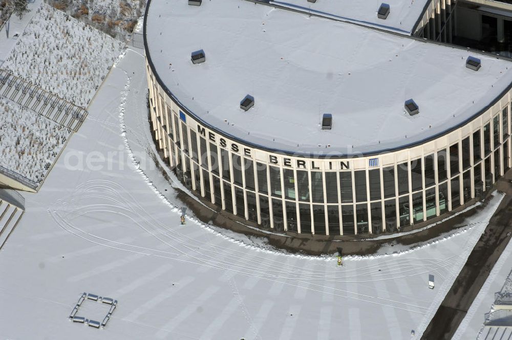 Aerial photograph Berlin - Blick auf den winterlich verschneiten Südeingang zum Messegelände am Berliner Funkturm. Das Messegelände in Berlin liegt im Ortsteil Westend des Bezirks Charlottenburg-Wilmersdorf zwischen der Masurenallee (gegenüber dem Haus des Rundfunks), dem Messedamm und der Jafféstraße. Das Areal umfasst 26 Messehallen mit 160.000 m² Hallenfläche. Die Hallen sind miteinan der verbunden und es ist möglich, mehrere Hallen für bestimmte Veranstaltungen – abhängig von der Größe – zusammenzufassen. Ein flexibles Leitsystem bietet dem Besucher Orientierung bei seinem Messebesuch.