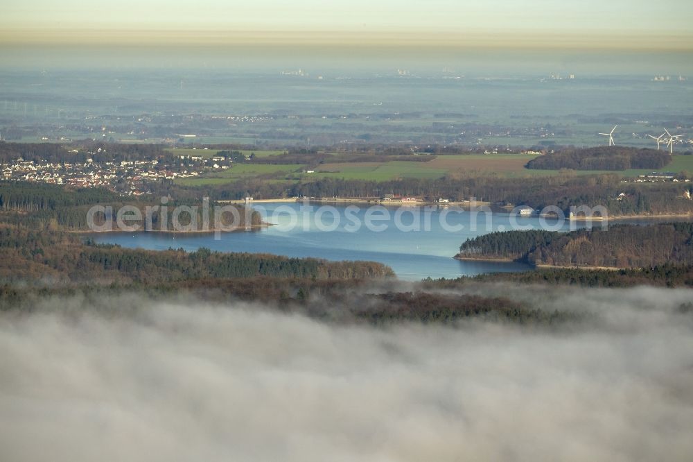 Aerial photograph Möhnesee - Landscape with view over the Moehnesee with ascending mist in the state North Rhine-Westphalia. The wall of the Moehnetalsperre is registered as a historic landmark