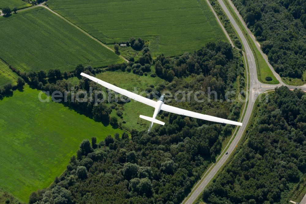 Aerial image Stade - Glider ASW 20 flying above meadows, a forest and a street near Stade in the state Lower Saxony, Germany