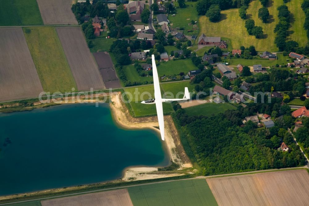 Stade from the bird's eye view: High performance glider ASW 20 in flight over the fields near Stade in Lower Saxony, Germany. An aluminum production waste product is deposited here