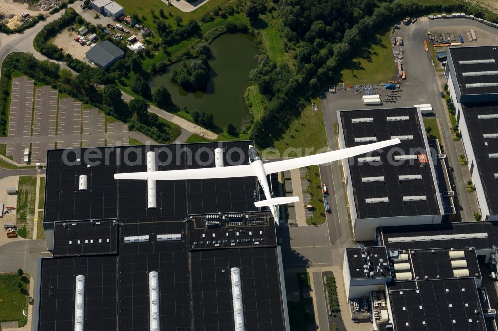 Aerial photograph Stade - Glider ASW 20 flying above the factory and the production halls of Airbus in Stade in the state Lower Saxony, Germany