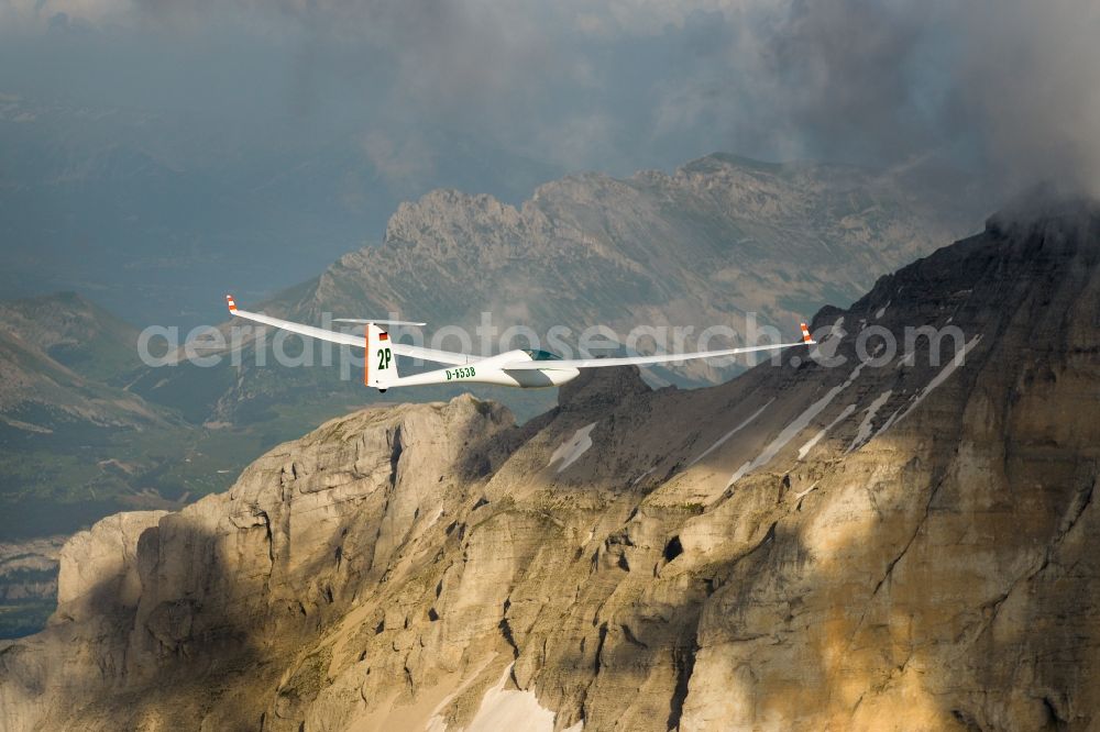 Aerial image Le Dévoluy - Glider ASW 20 D-6538 in flight over the rugged mountain peaks under low-hanging clouds of the Pic de Bure in the Provence-Alpes-Cote d'Azur, France