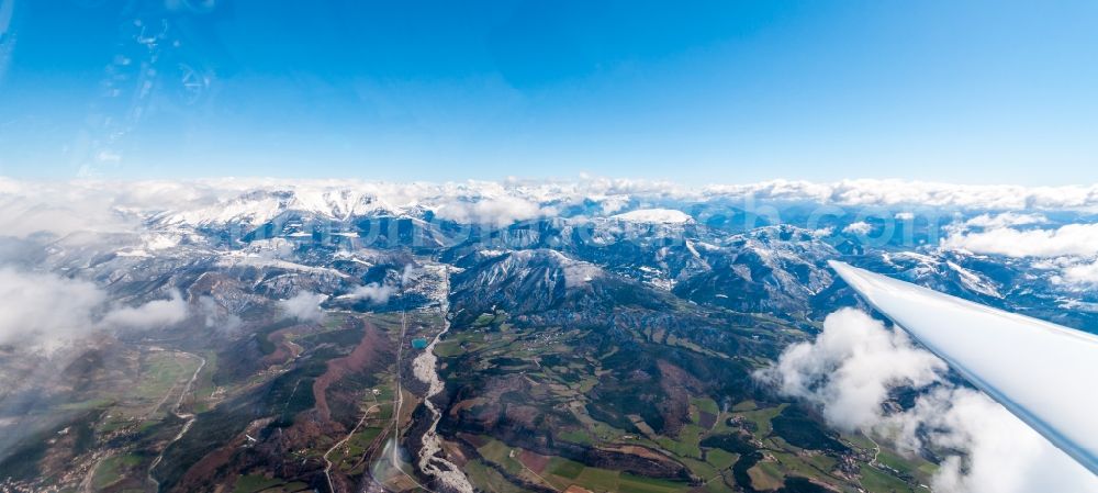 Aspremont from the bird's eye view: Glider in flight above the clouds and snowy mountains of the French Maritime Alps in Aspremont in Provence-Alpes-Cote d'Azur, France