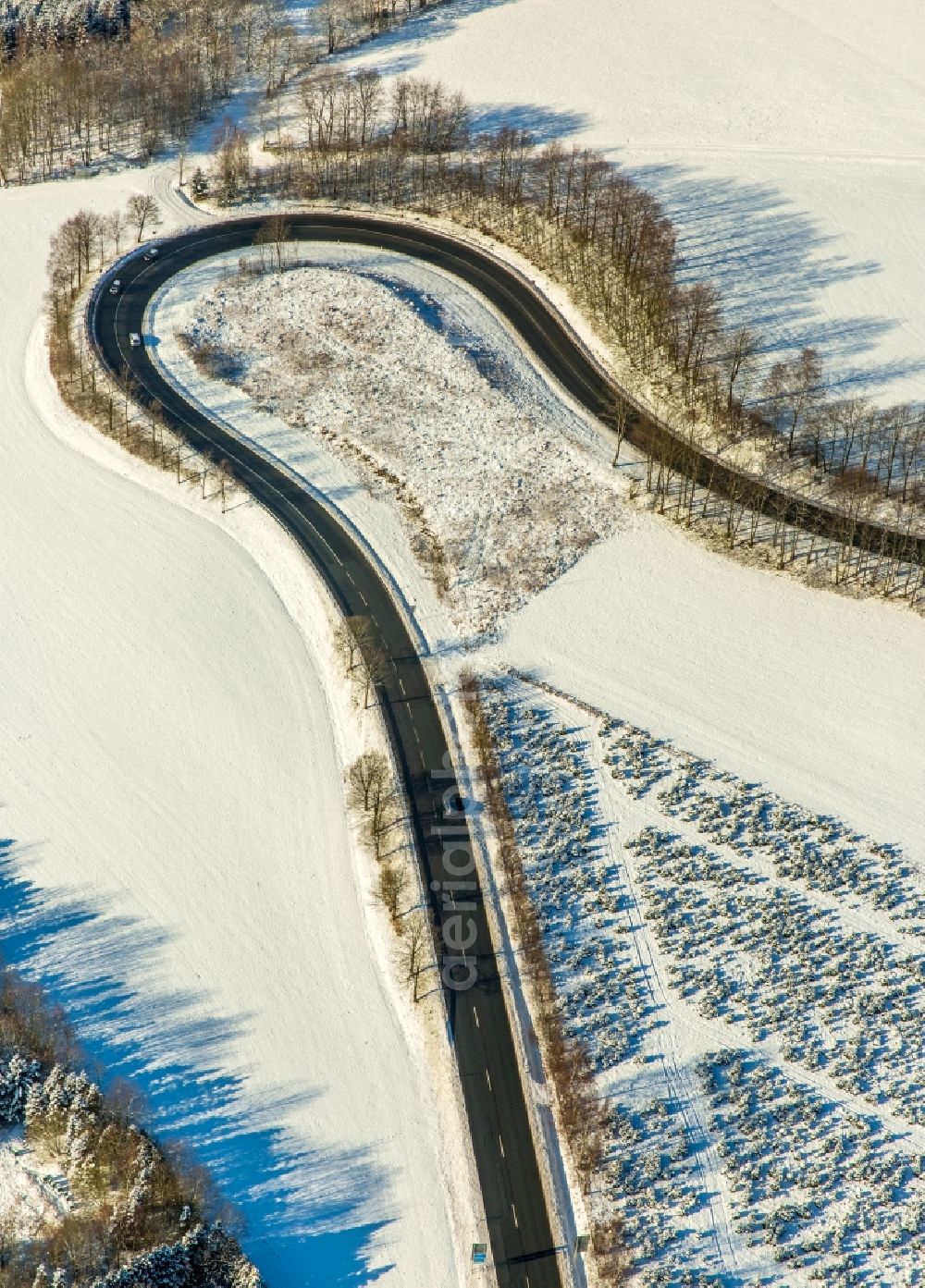 Olsberg from the bird's eye view: Wintry snowy serpentine-shaped curve of a road guide in Olsberg in the state North Rhine-Westphalia