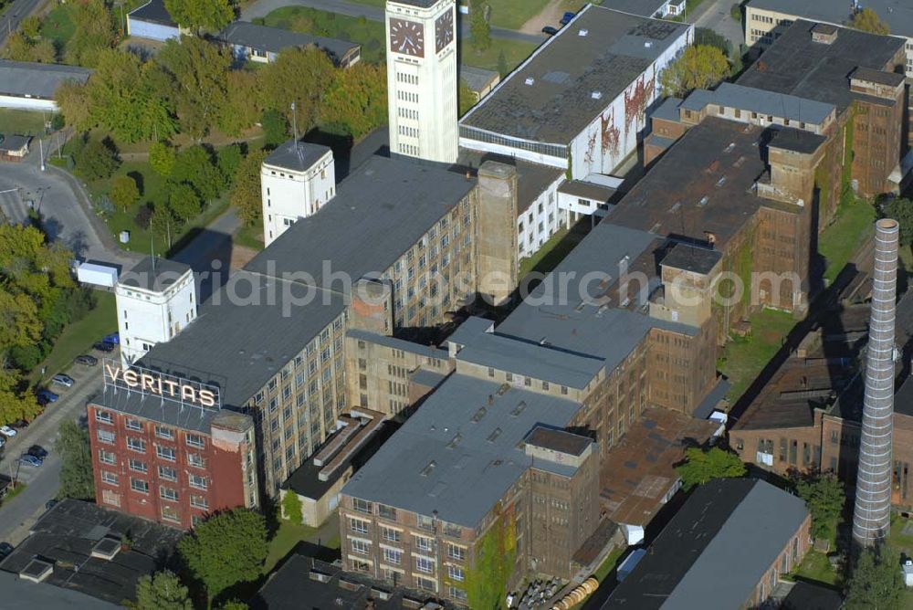 Aerial photograph Wittenberge - Blick auf das Gebäude der Firma Veritas an der Bad Wilsnacker Straße. Nach der Demontage des Singer-Werkes wurde die Herstellung unter dem Namen Veritas mit viel Kraftaufwand weitergeführt. Der Uhrenturm des ehemaligen Nähmaschinenwerkes SINGER/VERITAS in Wittenberge ist die größte Turmuhr Deutschlands und zweitgrößte Turmuhr in Europa – nach Big Ben in London. Die architektonischen Formen des gelb verputzten Turms lassen eine Beeinflussung durch den Expressionismus und vor allem die Neue Sachlichkeit erkennen. Bis zu 3.000 Menschen arbeiteten in dieser Fabrik, die 1990, in ihrem letzten Jahr, noch 400.000 Nähmaschinenwerk Haushaltsnähmaschinen produzierte.