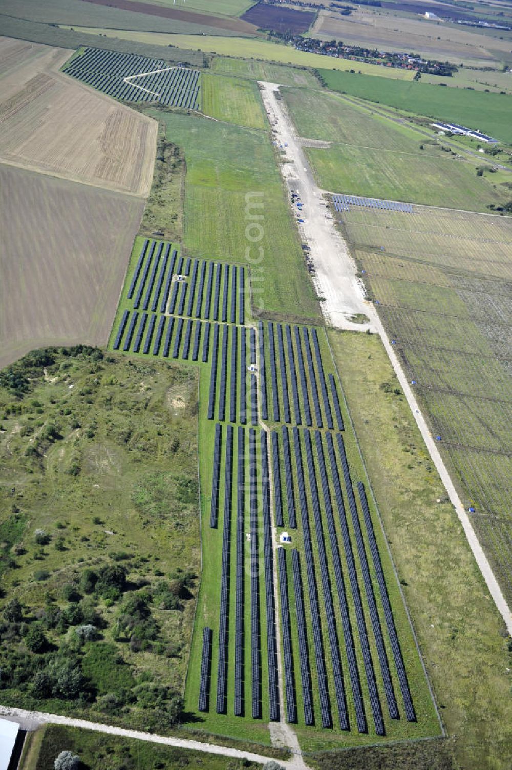 Köthen from above - Blick auf den Solarpark auf dem Flugplatz Köthen. Auf einer Fläche von 55 Hektar ist es das bundesweit zweitgrößte Photovoltaik-Kraftwerk und wurde 2008 in Betrieb genommen. Die hochmoderne PV-Anlage besteht aus ca. 200.000 dünnschicht Solarmodulen der Firma First Solar. Betrieben wird das Feld von der juwi solar GmbH. Solar Park at the former airfield Köthen.