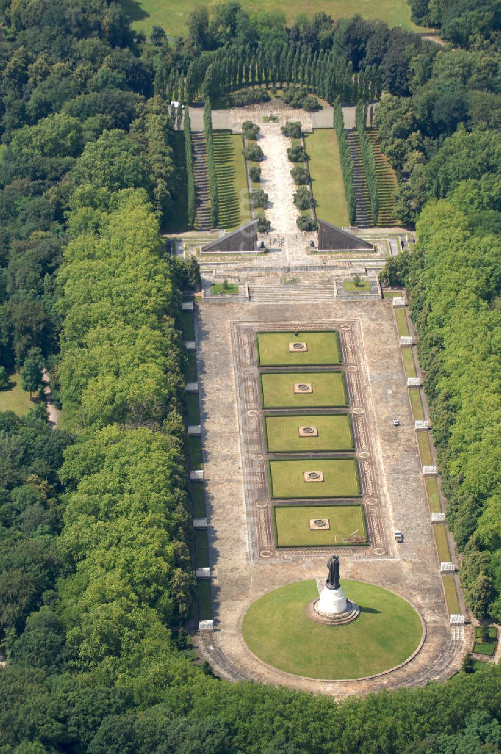 Aerial photograph Berlin - Blick auf das Zentrum des Sowjetischen Ehrenmals, der Skulptur des Befreiers. Diese besteht aus dem Ehrenhügel, der darin befindlichen Kuppel, die als Mausoleum dient, sowie der Statue eines Soldaten der Roten Armee. Inspiriert ist die Statue durch die angebliche Tat eines Sowjetsoldaten, der unter Beschuss ein kleines Mädchen retten konnte. Das gesamte Ehrenmal wurde 1949 errichtet und befindet sich im Treptower Park, erreichbar über die beiden Eingänger am Treptower Park und der Puschinallee.