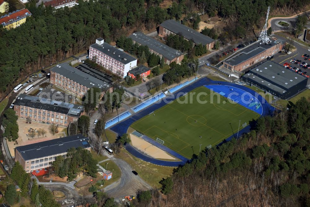 Kleinmachnow from above - Sports facilities of the Berlin Brandenburg International School and residential buildings in Kleinmachnow in the state of Brandenburg. The BBIS includes a football pitch and athletics facilities in a distinct blue colour. Residential buildings and estates as well as a primary school are surrounded by trees and woods