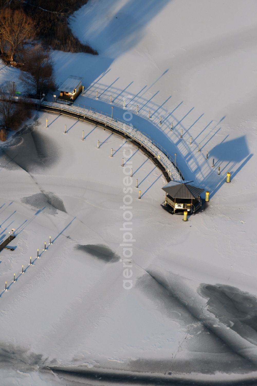 Beetzsee from above - Recreational marine jetties and moorings on the shore area of the wintry snow and ice covered Beetzsee in Brandenburg