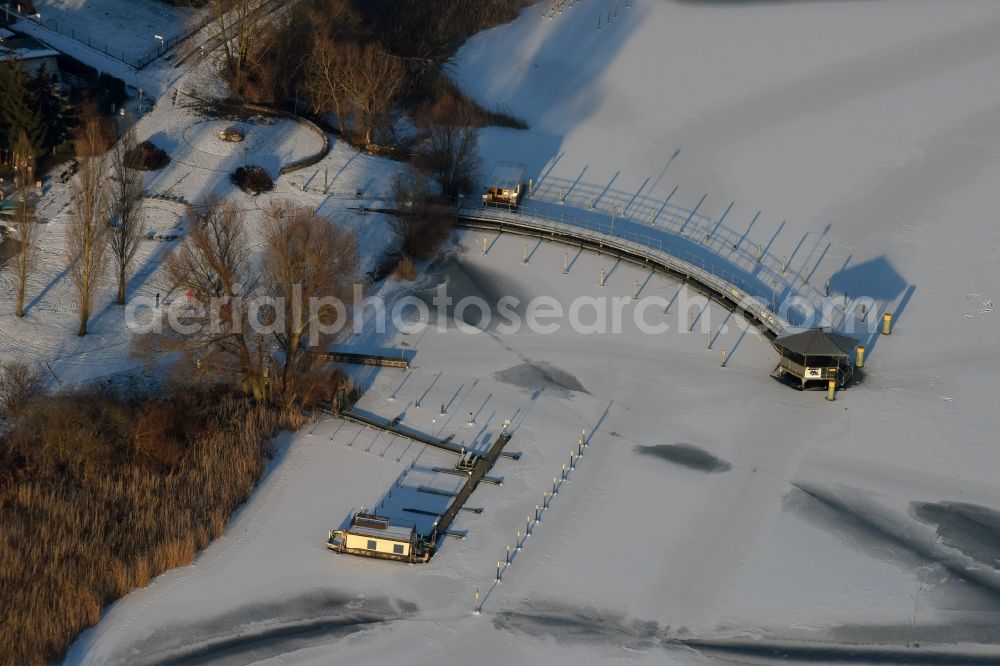 Aerial image Beetzsee - Recreational marine jetties and moorings on the shore area of the wintry snow and ice covered Beetzsee in Brandenburg