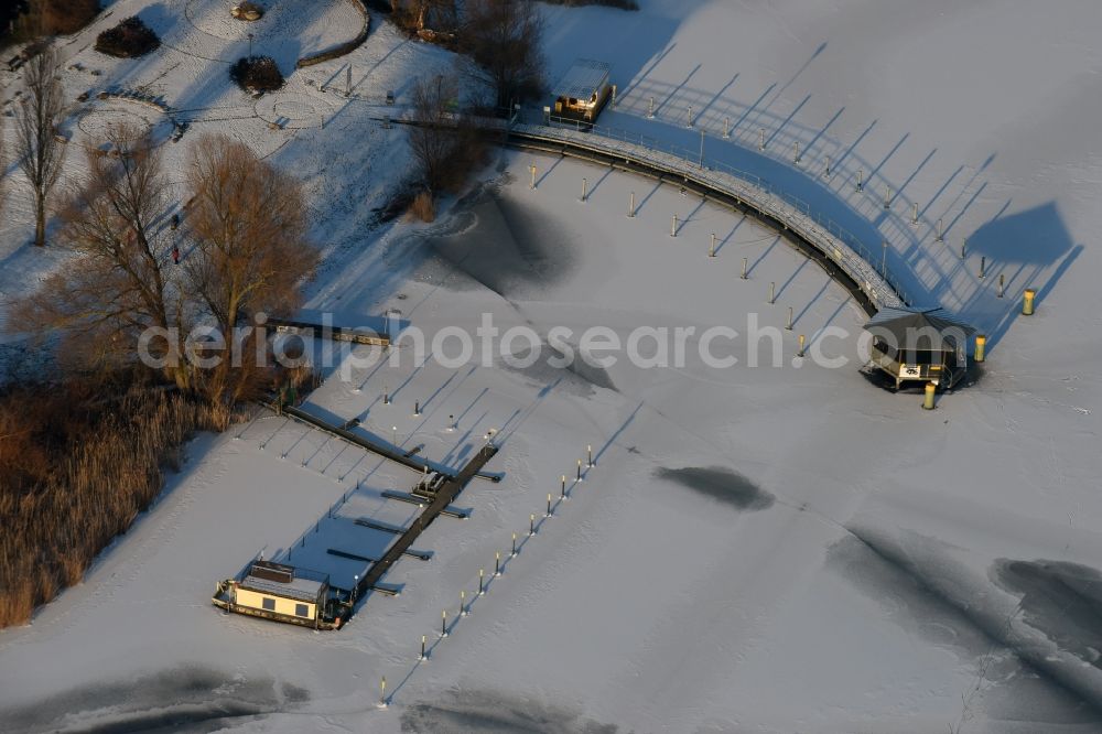 Aerial photograph Beetzsee - Recreational marine jetties and moorings on the shore area of the wintry snow and ice covered Beetzsee in Brandenburg