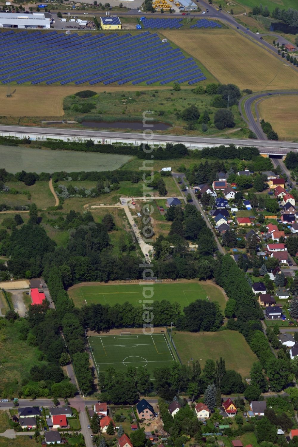 Neuenhagen from the bird's eye view: View of the sports fields between some residences and the solar park in the industrial area in Neuenhagen at the Berliner Ring German freeway A10 E55 in the state Brandenburg