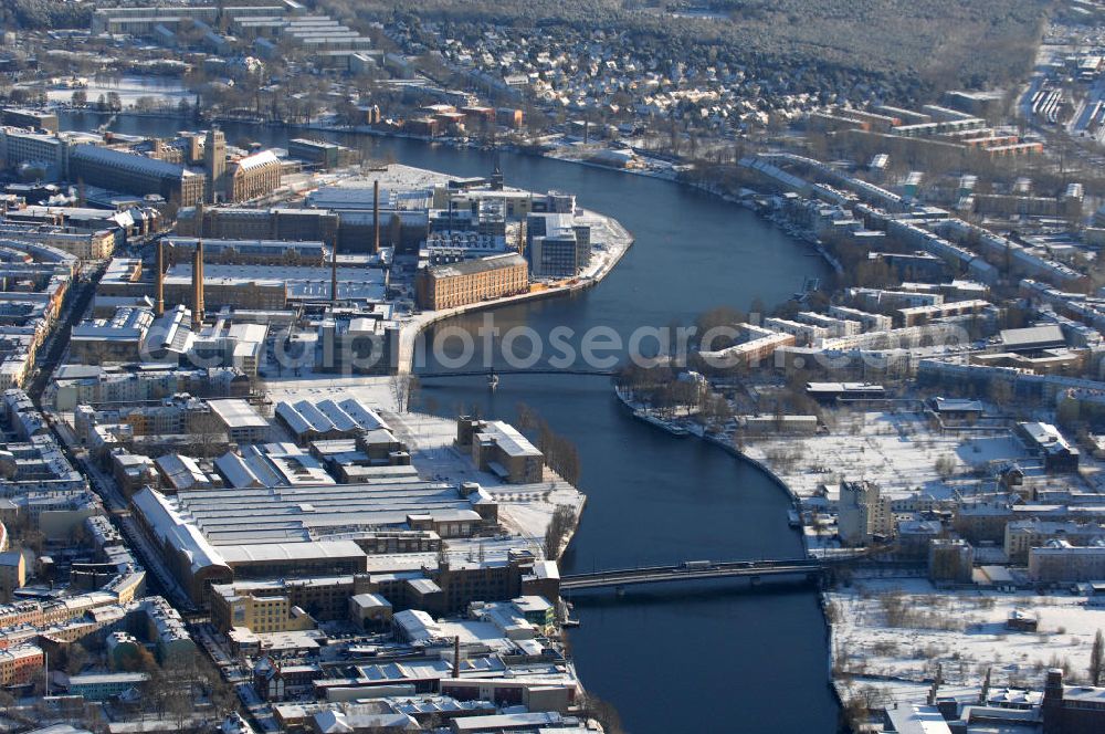 Berlin from above - Blick auf die Spree mit den winterlich Schnee bedeckten Stadtteilen Oberschöneweide (l) und Niederschöneweide (r). Die beiden Stadtteile sind über die Straßenbrücke Neue Treskowbrücke (v) und über die Fussgängerbrücke Kaisersteg (h) miteinan der verbunden.