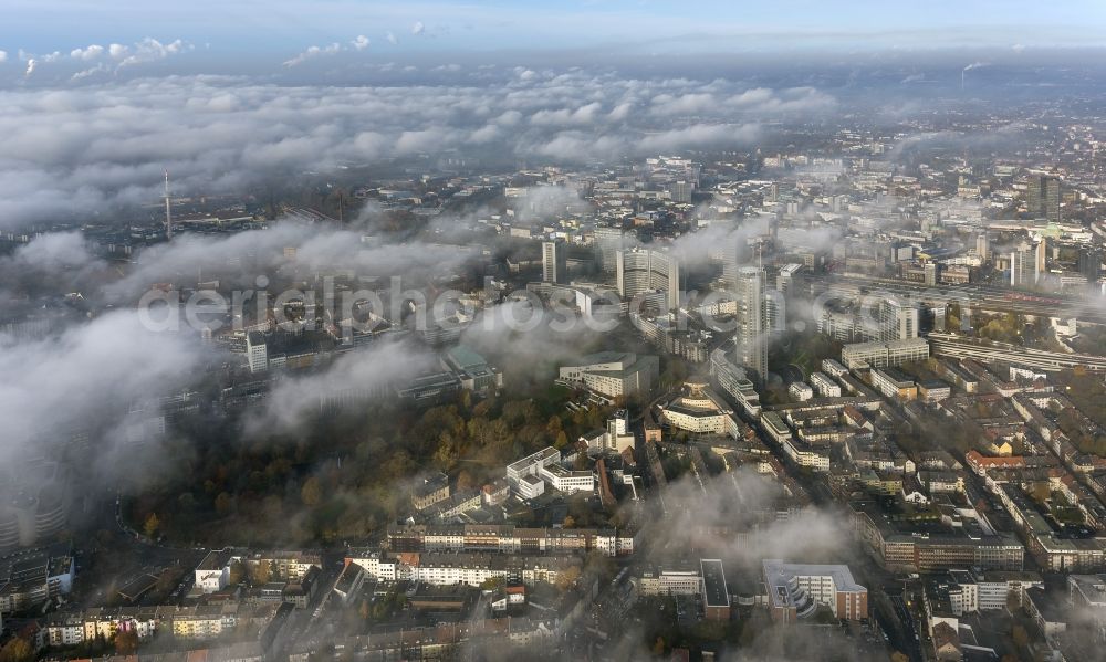 Aerial photograph Essen - Stadtansicht über die von einer imposanten Nebel- und Wolken- Landschaft eingehüllte Skyline der Essener Innenstadt im Bundesland Nordrhein-Westfalen NRW. Die Herbt Wetter Wolken überziehen die Stadt im Ruhrgebiet mit einer dichten Wolkendecke und umschließen u.a. das Rathaus und den Sitz des Energieversorgers RWE im RWE- Turm am Opernplatz. / Cityscape overlooking the skyline of the Essen city center shrouded by an impressive landscape of fog and clouds in the state North Rhine-Westphalia. The autumn weather clouds cover the Ruhr region city with a thick blanket of clouds and surround among others the townhall and the RWE Tower at Opernplatz.