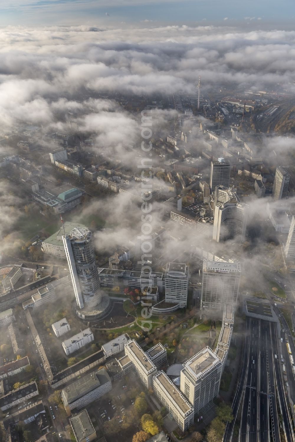 Essen from above - Stadtansicht über die von einer imposanten Nebel- und Wolken- Landschaft eingehüllte Skyline der Essener Innenstadt im Bundesland Nordrhein-Westfalen NRW. Die Herbt Wetter Wolken überziehen die Stadt im Ruhrgebiet mit einer dichten Wolkendecke und umschließen u.a. das Rathaus und den Sitz des Energieversorgers RWE im RWE- Turm am Opernplatz. / Cityscape overlooking the skyline of the Essen city center shrouded by an impressive landscape of fog and clouds in the state North Rhine-Westphalia. The autumn weather clouds cover the Ruhr region city with a thick blanket of clouds and surround among others the townhall and the RWE Tower at Opernplatz.