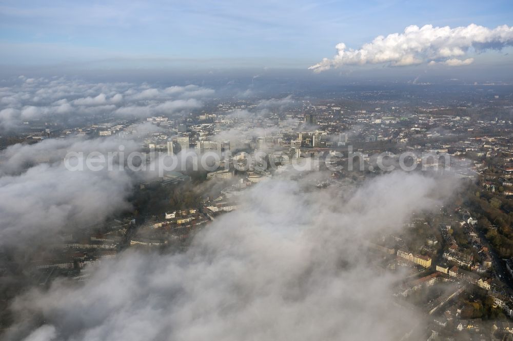 Essen from the bird's eye view: Stadtansicht über die von einer imposanten Nebel- und Wolken- Landschaft eingehüllte Skyline der Essener Innenstadt im Bundesland Nordrhein-Westfalen NRW. Die Herbt Wetter Wolken überziehen die Stadt im Ruhrgebiet mit einer dichten Wolkendecke und umschließen u.a. das Rathaus und den Sitz des Energieversorgers RWE im RWE- Turm am Opernplatz. / Cityscape overlooking the skyline of the Essen city center shrouded by an impressive landscape of fog and clouds in the state North Rhine-Westphalia. The autumn weather clouds cover the Ruhr region city with a thick blanket of clouds and surround among others the townhall and the RWE Tower at Opernplatz.