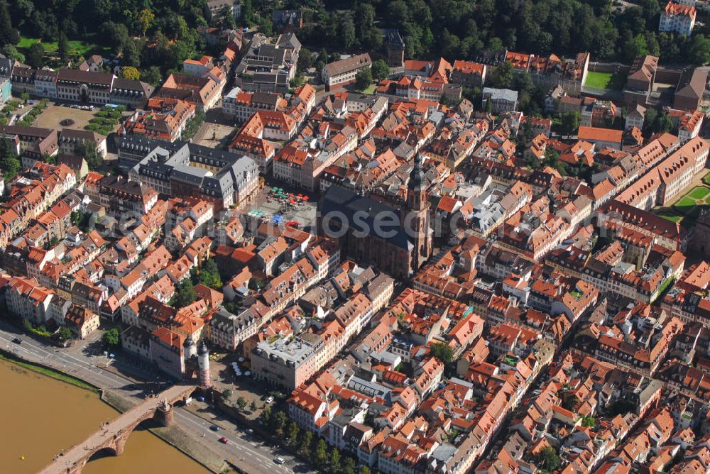 Heidelberg from the bird's eye view: Stadtansicht mit Blick auf die Heiliggeistkirche in Heidelberg. Die Heiliggeistkirche ist die bekannteste Kirche von Heidelberg. Sie steht am Marktplatz mitten im alten Zentrum von Heidelberg, nur unweit vom Heidelberger Schloss entfernt und beherrscht mit ihrer weit über die Dächer ragenden Silhouette das ganze Stadtbild. Die Heiliggeistkirche wurde 1239 zum ersten Mal erwähnt. 1398 wurde der Grundstein für ihre heutige, spätgotische Form gelegt, welche die damalige spätromanische Basilika gleichen Namens ersetzte, die selbst auch nicht der ursprüngliche Bau war. Kontakt: Heiliggeistkirche, Heiliggeiststr. 17, 69117 Heidelberg, Tel.: 06221 21117, http://heiliggeist.ekihd.de