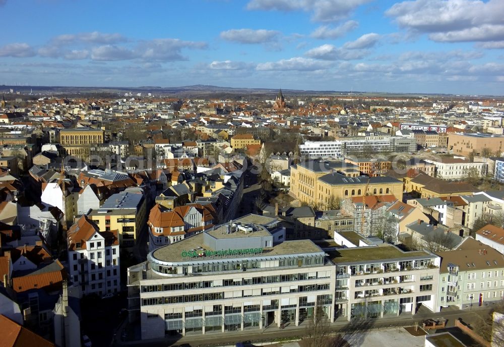 Aerial photograph Halle - Im Vordergrund der Stadtansicht Halle-Saale im Bundesland Sachsen-Anhalt steht das Bürogebäude der ÖSA-Versicherung in der Adam-Kuckhoff-Straße. Der markante ockerfarbene Bau mit u-förmigen Grundriss ist die Integrierte Gesamtschule Halle. Aus dem Altbauviertel erhebt sich der Kirchturm der Pauluskirche, der dem umliegenden Wohnviertel den Namen gibt. Am Horizont ist der Petersberg zu erkennen. //In the foreground of the view Halle-Saale in Saxony-Anhalt is the office building of OSA insurance in the Adam Kuckhoff Street. The distinctive ocher-colored building with a U-shaped floor plan is the comprehensive school Halle. From the old district, the steeple of St. Paul's, which gives the surrounding residential area the name rises. On the horizon of the Petersberg be seen