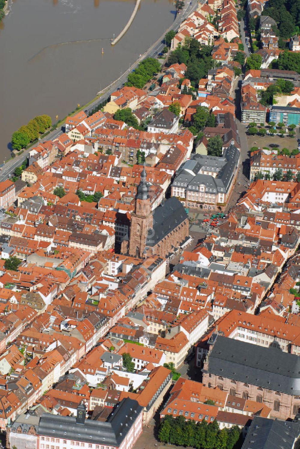 Aerial image Heidelberg - Stadtansicht mit Blick auf zwei Kirchen Heidelbergs. Heidelberg ist eine Großstadt am Neckar im Südwesten Deutschlands. Mit über 140.000 Einwohnern ist Heidelberg die fünftgrößte Stadt Baden-Württembergs. Sie ist kreisfreie Stadt und zugleich Sitz des umliegenden Rhein-Neckar-Kreises. Die Heiliggeistkirche (mitte) ist die bekannteste Kirche von Heidelberg. Sie steht am Marktplatz mitten im alten Zentrum von Heidelberg, nur unweit vom Heidelberger Schloss entfernt und beherrscht mit ihrer weit über die Dächer ragenden Silhouette das ganze Stadtbild. Die Heiliggeistkirche wurde 1239 zum ersten Mal erwähnt. 1398 wurde der Grundstein für ihre heutige, spätgotische Form gelegt, welche die damalige spätromanische Basilika gleichen Namens ersetzte, die selbst auch nicht der ursprüngliche Bau war. Kontakt: Heiliggeistkirche, Heiliggeiststr. 17, 69117 Heidelberg, Tel.: 06221 21117, http://heiliggeist.ekihd.de. Unweit der Heiliggeistkirche befindet sich auch die Jesuitenkirche (unten). Sie ist das Wahrzeichen der Gegenreformation in Heidelberg und bildete einst den Mittelpunkt des ehemaligen Jesuitenviertels. Sie ist heute die Hauptkirche der römisch-katholischen Heilig-Geist-Gemeinde. Der Bau der Jesuitenkirche wurde in den Jahren 1712 bis 1723 unter der Leitung von Johann Adam Breuning begonnen. Die Fertigstellung erfolgte jedoch erst 1759 unter dem Architekten des kurpfälzischen Hofes, Franz Wilhelm Rabaliatti. 1793 - 1797 wurde die Jesuitenkirche als Lazarett für Verwundete des ersten Koalitionskrieges genutzt. Kontakt: Jesuitenkirche Heidelberg, Merianstr. 2, 69117 Heidelberg, Tel.: 06221 / 9008-0,