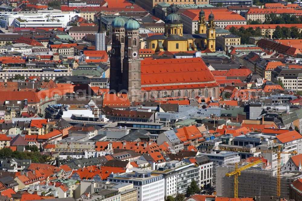 Aerial photograph München - Stadtansicht München mit Blick auf die Frauenkirche. Die Frauenkirche ist die Kathedralkirche des Erzbischofs von München und Freising und gilt als Wahrzeichen der bayerischen Landeshauptstadt. Der dreischiffige spätgotische Backsteinbau mit umlaufendem Kapellenkranz ist 109 m lang, 40 m breit und 37 m hoch. Die Kirche bietet etwa 20.000 stehenden Menschen Platz, was erstaunlich ist, wenn man bedenkt, dass die Stadt zur Bauzeit im ausgehenden 15. Jh. nur etwa 13.000 Einwohner hatte. Die Grundsteinlegung für die heutige Frauenkirche - die wahrscheinlich bereits einen kleineren Vorgänger hatte, den sie ersetzte - erfolgte im Jahr 1468 durch Herzog Sigismund. Da man aus Kostengründen einen gemauerten Backsteinbau errichten wollte, statt auf teure Steinmetzarbeiten zurück zu greifen, wurde die Leitung der Bauarbeiten Jörg von Halspach, einem Maurermeister, übertragen. Im Jahr 1494 wurde die Frauenkirche geweiht. Im Zweiten Weltkrieg schwer beschädigt, wurde die Kirche in der Nachkriegszeit wieder aufgebaut, dabei erhielt sie ihr heutiges eher nüchternes, aber dennoch gewaltiges und markantes Äußeres. Von der ursprünglichen Ausstattung sind noch einige mittelalterliche Skulpturen und die mittelalterlichen Glasgemälde der Chorfenster erhalten geblieben. Mit ihrer herrlichen zentralen Lage inmitten einer großzügigen Fußgängerzone, die zwischen Karlsplatz und Marienplatz eingerichtet wurde, ist die Frauenkirche eine der meistbesuchtesten Sehenswürdigkeiten Münchens. Kontakt: Dom Zu Unserer Lieben Frau, Frauenplatz 12, 80331 München, Tel.: 089/290082-0, E-Mail: dompfarramt@muenchner-dom.de,