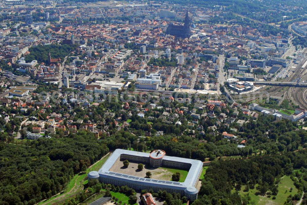 Ulm from the bird's eye view: Stadtansicht Ulm mit Blick auf die Bundesfestung Ulm. Im Hintergrund ist das Ulmer Münster zu sehen. Die Bundesfestung Ulm ist, neben Landau, Luxemburg, Mainz und Rastatt, eine von fünf Bundesfestungen. Diese Festungen wurden durch den deutschen Bund finanziert und, neben zahlreichen Landesfestungen, im 19. Jh. aus- oder neu gebaut. Die Bundesfestung Ulm wurde im Zeitraum von 1838 bis 1859 von Festungsbaudirektor und damaligem Oberst Moritz Karl Ernst von Prittwitz und Gaffron entworfen und unter seiner Leitung erbaut. In Friedenszeiten sollte die Festung 5.000 Soldaten des Bundesheeres beherbergen, für den Eintritt des Ernstfalles rechnete man dagegen mit bis zu 20.000 Soldaten. Die Festung stellt sich als geschlossener, polygonförmiger Mauerzug um beide Städte Ulm und Neu-Ulm dar, der in einiger Entfernung eine Reihe Forts vorgelagert sind. Die Wilhelmsburg wurde von 1842 bis 1849 als Reduit der Zitadelle der Festung Ulm erbaut. Soldaten waren noch bis 1970 in den Kasematten der Wilhelmsburg untergebracht. Seither stehen die rund 570 Räume leer. Viele Probleme gibt es bei der Erhaltung der Festungsanlagen. Eine sinnvolle, denkmalgerechte Nutzung hilft, den Bauunterhalt für die Zukunft zu sichern. Das gilt auch für die Freianlagen der Forts. Beträchtliche Teile wurden schon von den beiden Städten und vom Bund restauriert und vor allem kulturellen Einrichtungen zur Verfügung gestellt. Kontakt: Förderkreis Bundesfestung Ulm e.V., Bahnwaldstr. 11, 89233 Neu-Ulm, E-Mail: vereinsvorstand@festung-ulm.de