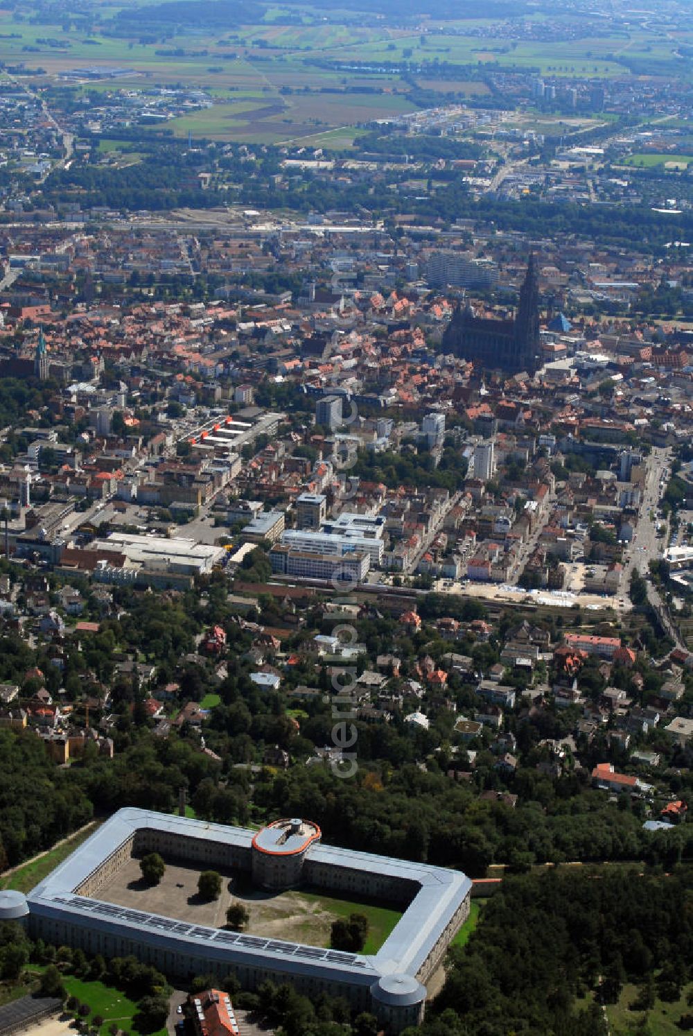 Aerial image Ulm - Stadtansicht Ulm mit Blick auf die Bundesfestung Ulm. Im Hintergrund ist das Ulmer Münster zu sehen. Die Bundesfestung Ulm ist, neben Landau, Luxemburg, Mainz und Rastatt, eine von fünf Bundesfestungen. Diese Festungen wurden durch den deutschen Bund finanziert und, neben zahlreichen Landesfestungen, im 19. Jh. aus- oder neu gebaut. Die Bundesfestung Ulm wurde im Zeitraum von 1838 bis 1859 von Festungsbaudirektor und damaligem Oberst Moritz Karl Ernst von Prittwitz und Gaffron entworfen und unter seiner Leitung erbaut. In Friedenszeiten sollte die Festung 5.000 Soldaten des Bundesheeres beherbergen, für den Eintritt des Ernstfalles rechnete man dagegen mit bis zu 20.000 Soldaten. Die Festung stellt sich als geschlossener, polygonförmiger Mauerzug um beide Städte Ulm und Neu-Ulm dar, der in einiger Entfernung eine Reihe Forts vorgelagert sind. Die Wilhelmsburg wurde von 1842 bis 1849 als Reduit der Zitadelle der Festung Ulm erbaut. Soldaten waren noch bis 1970 in den Kasematten der Wilhelmsburg untergebracht. Seither stehen die rund 570 Räume leer. Viele Probleme gibt es bei der Erhaltung der Festungsanlagen. Eine sinnvolle, denkmalgerechte Nutzung hilft, den Bauunterhalt für die Zukunft zu sichern. Das gilt auch für die Freianlagen der Forts. Beträchtliche Teile wurden schon von den beiden Städten und vom Bund restauriert und vor allem kulturellen Einrichtungen zur Verfügung gestellt. Kontakt: Förderkreis Bundesfestung Ulm e.V., Bahnwaldstr. 11, 89233 Neu-Ulm, E-Mail: vereinsvorstand@festung-ulm.de