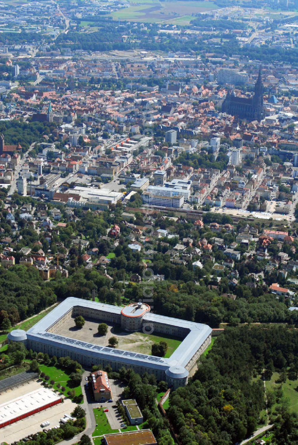 Aerial photograph Ulm - Stadtansicht Ulm mit Blick auf die Bundesfestung Ulm. Im Hintergrund ist das Ulmer Münster zu sehen. Die Bundesfestung Ulm ist, neben Landau, Luxemburg, Mainz und Rastatt, eine von fünf Bundesfestungen. Diese Festungen wurden durch den deutschen Bund finanziert und, neben zahlreichen Landesfestungen, im 19. Jh. aus- oder neu gebaut. Die Bundesfestung Ulm wurde im Zeitraum von 1838 bis 1859 von Festungsbaudirektor und damaligem Oberst Moritz Karl Ernst von Prittwitz und Gaffron entworfen und unter seiner Leitung erbaut. In Friedenszeiten sollte die Festung 5.000 Soldaten des Bundesheeres beherbergen, für den Eintritt des Ernstfalles rechnete man dagegen mit bis zu 20.000 Soldaten. Die Festung stellt sich als geschlossener, polygonförmiger Mauerzug um beide Städte Ulm und Neu-Ulm dar, der in einiger Entfernung eine Reihe Forts vorgelagert sind. Die Wilhelmsburg wurde von 1842 bis 1849 als Reduit der Zitadelle der Festung Ulm erbaut. Soldaten waren noch bis 1970 in den Kasematten der Wilhelmsburg untergebracht. Seither stehen die rund 570 Räume leer. Viele Probleme gibt es bei der Erhaltung der Festungsanlagen. Eine sinnvolle, denkmalgerechte Nutzung hilft, den Bauunterhalt für die Zukunft zu sichern. Das gilt auch für die Freianlagen der Forts. Beträchtliche Teile wurden schon von den beiden Städten und vom Bund restauriert und vor allem kulturellen Einrichtungen zur Verfügung gestellt. Kontakt: Förderkreis Bundesfestung Ulm e.V., Bahnwaldstr. 11, 89233 Neu-Ulm, E-Mail: vereinsvorstand@festung-ulm.de