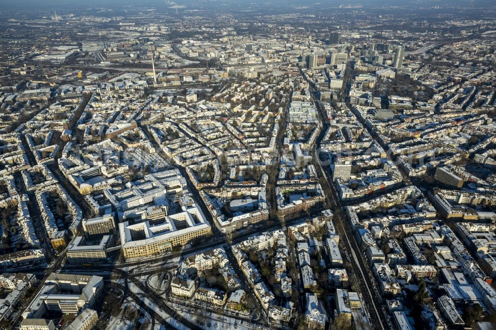 Aerial image Essen - Cityscape of the winterly and snow-covered Ruettenscheid part of Essen in the state of North Rhine-Westphalia. The district is located in the South of downtown Essen and is home to several symmetrical, almost rectangular, apartment blocks. It is also home to several public institutions and buildings such as the police headquarters, court buildings, a prison and a clinic for forensic psychiatry