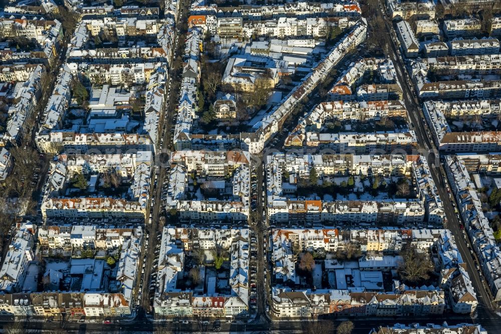 Essen from the bird's eye view: Cityscape of the winterly and snow-covered Ruettenscheid part of Essen in the state of North Rhine-Westphalia. The district is located in the South of downtown Essen and is home to several symmetrical, almost rectangular, apartment blocks. It is also home to several public institutions and buildings such as the police headquarters, court buildings, a prison and a clinic for forensic psychiatry