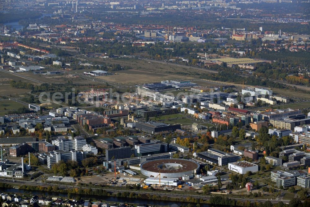 Aerial photograph Berlin - View of the Adlershof part and Technologypark in the Treptow-Koepenick district of Berlin in Germany. Adlershof consists of the technology park and industrial area and wide green areas and residential estates. The foreground shows the round Bessy II building - a research facility of Helmholtz Zentrum Berlin