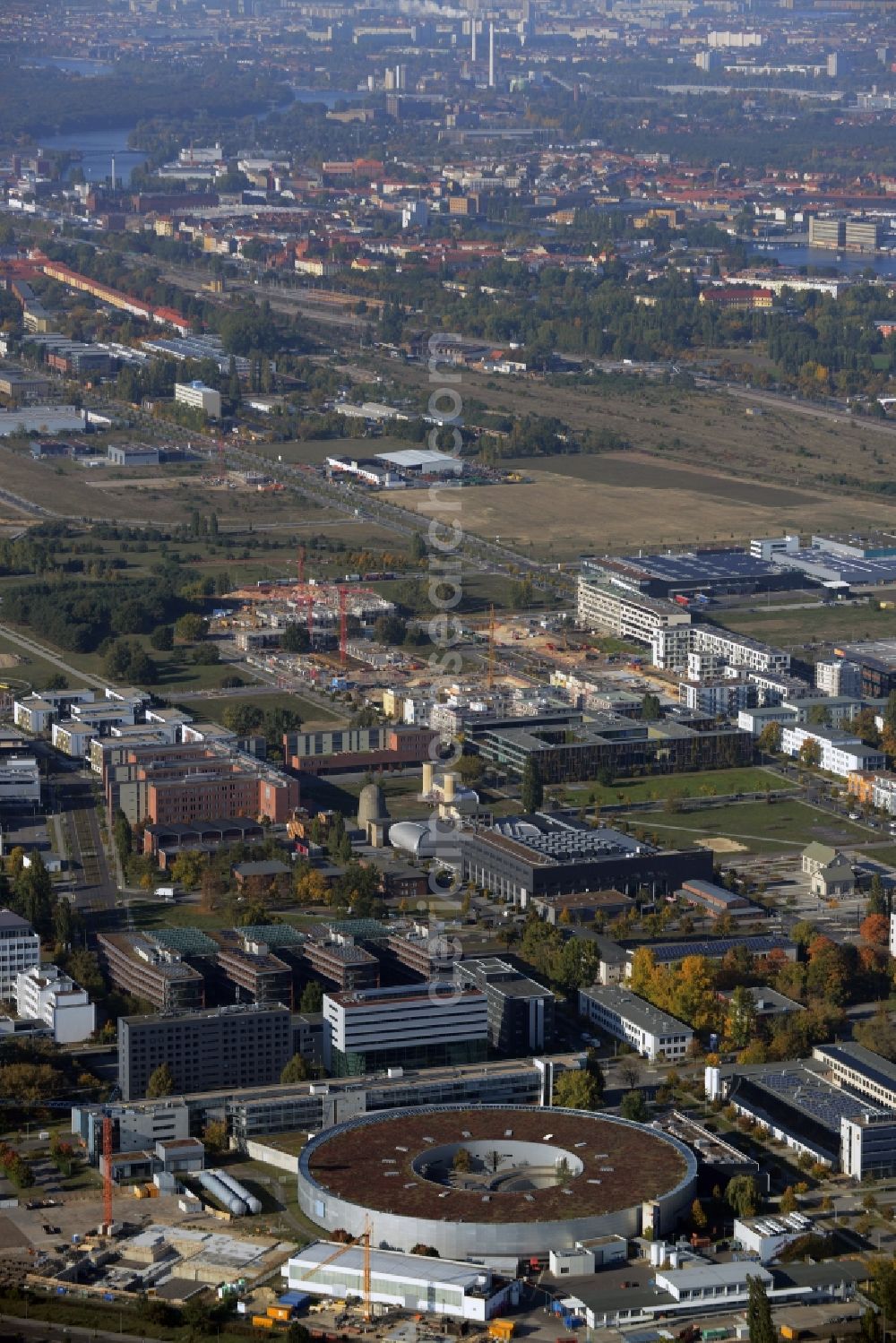 Berlin from above - View of the Adlershof part and Technologypark in the Treptow-Koepenick district of Berlin in Germany. Adlershof consists of the technology park and industrial area and wide green areas and residential estates. The foreground shows the round Bessy II building - a research facility of Helmholtz Zentrum Berlin