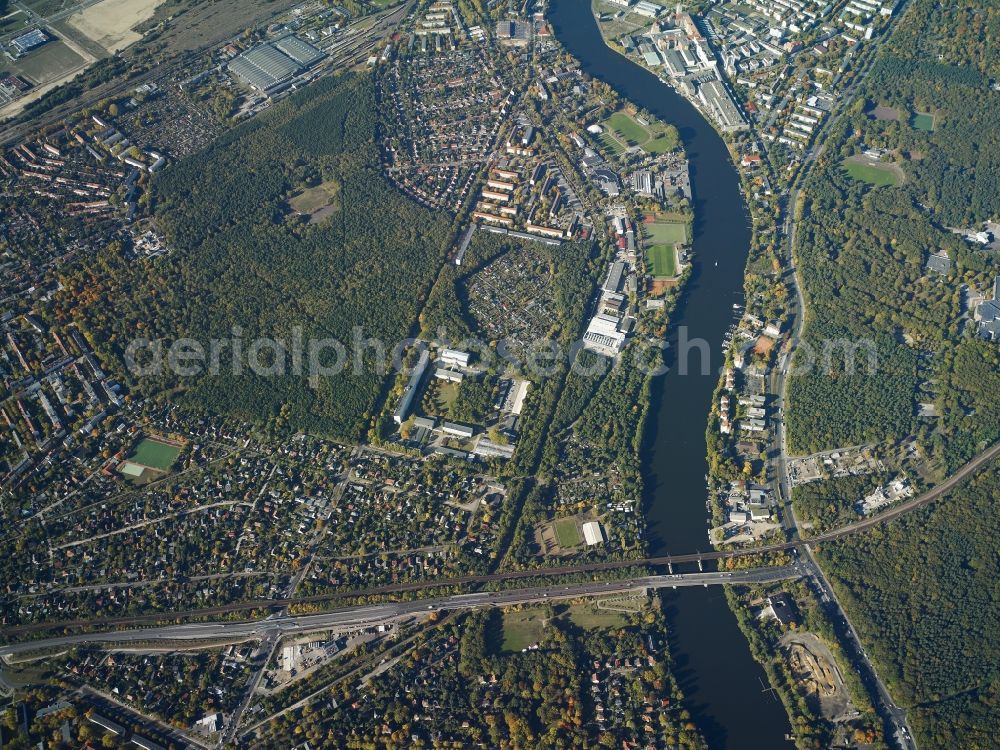 Berlin from the bird's eye view: View of the West of the Berlin-Koepenick part of the district of Treptow-Koepenick in Berlin. Several sports facilities, appartment blocks and estates and commerce areas are located on the river Spree which takes its course along the Wuhlheide forest region. A bridge with the Spindlersfelder street spans the river and joins the street An der Wuhlheide in the North of the river. A separate overground bridge spans the river as well