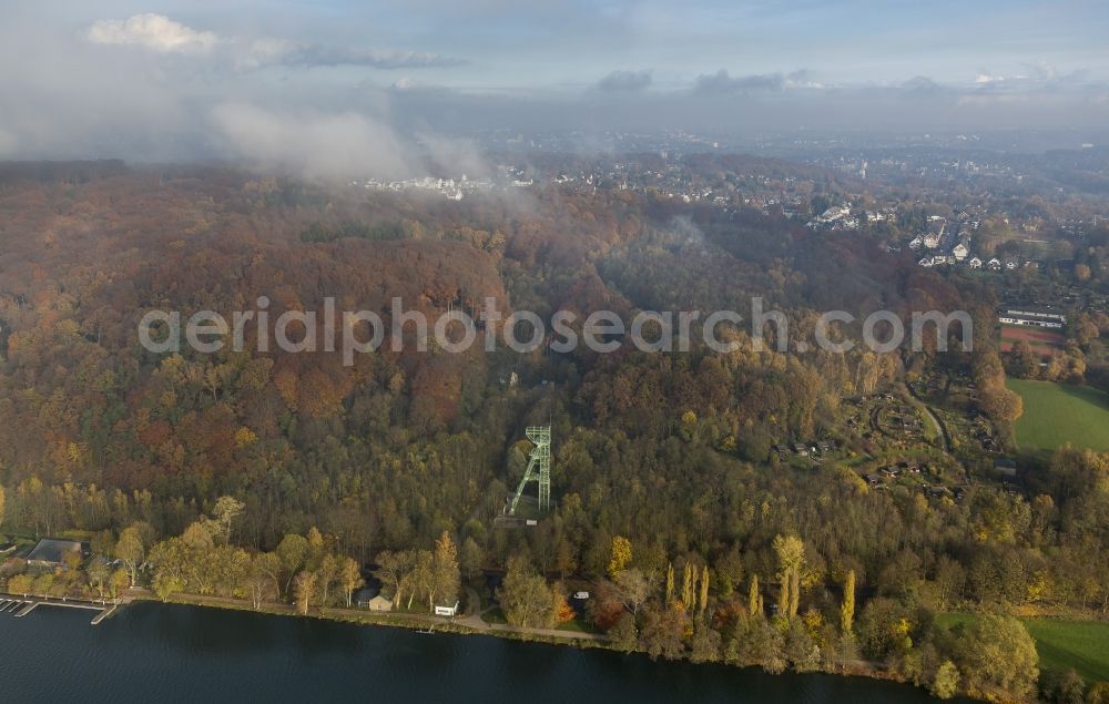 Essen from the bird's eye view: View of the city forest with autumnal foliage on the Ruhr peninsular Heisingen covered by fog and autumn weather clouds in Essen in the state North Rhine-Westphalia. The western shore of the peninsular is located at the banks of the lake Baldeneysee. Visible is the headframe of former coal mine pit Carl Funke